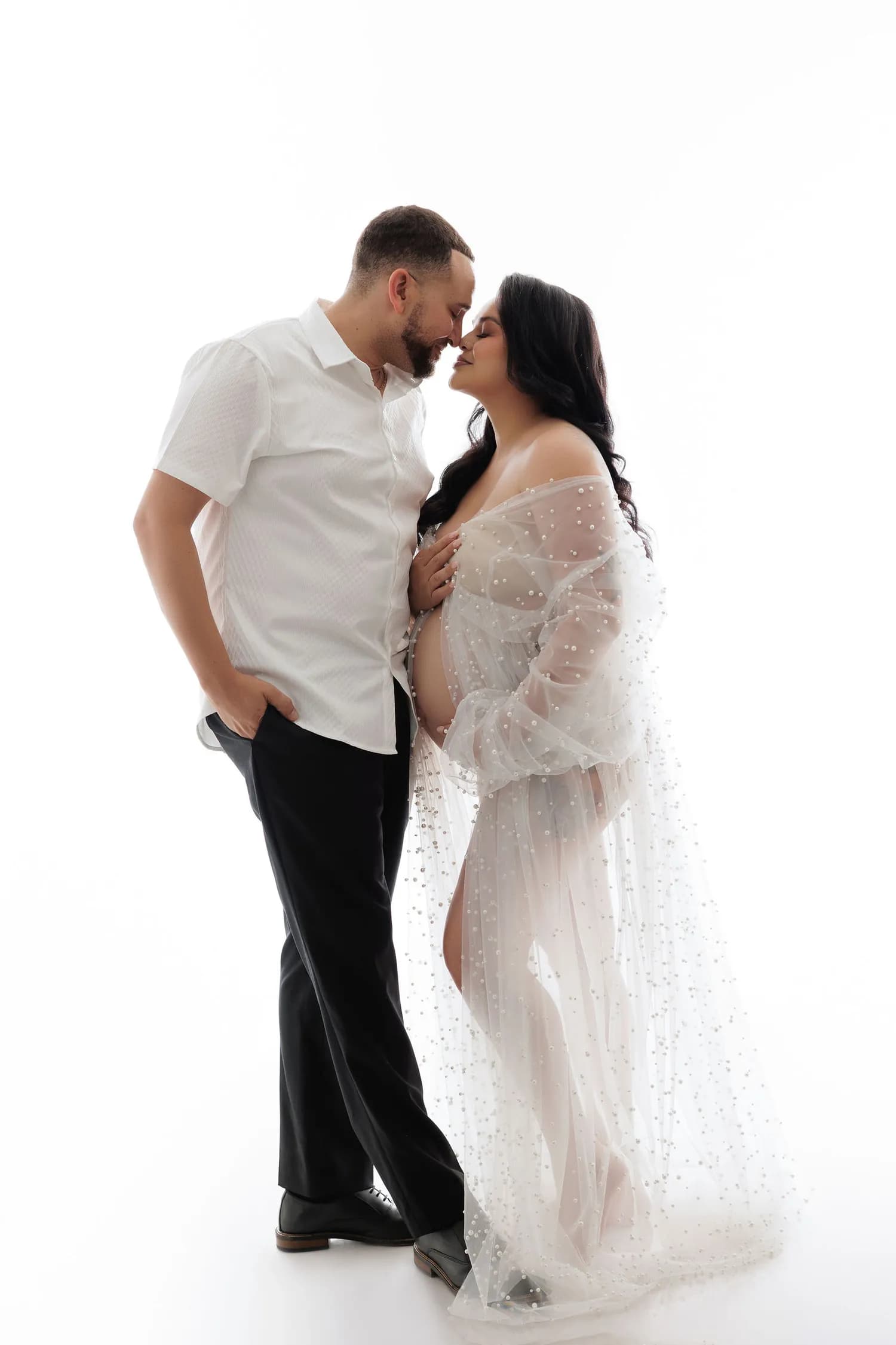 Couple nose to nose, the pregnant woman in a sheer pearl robe, on a white background