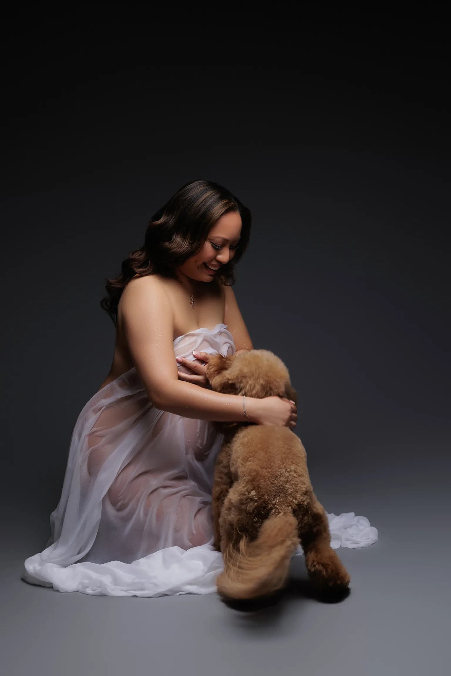 An expectant mother photographed in the studio with her dog